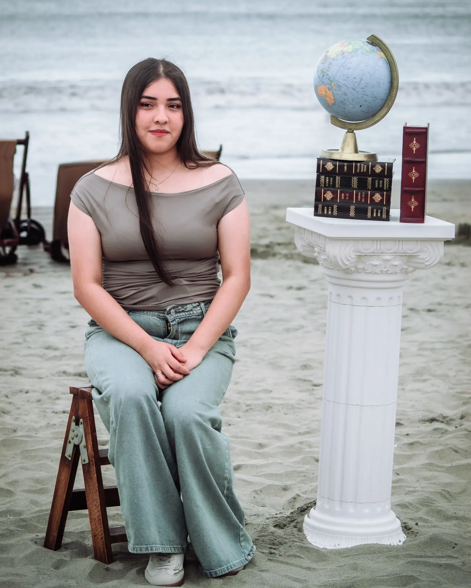 Mujer sentada con un globo terráqueo en la playa