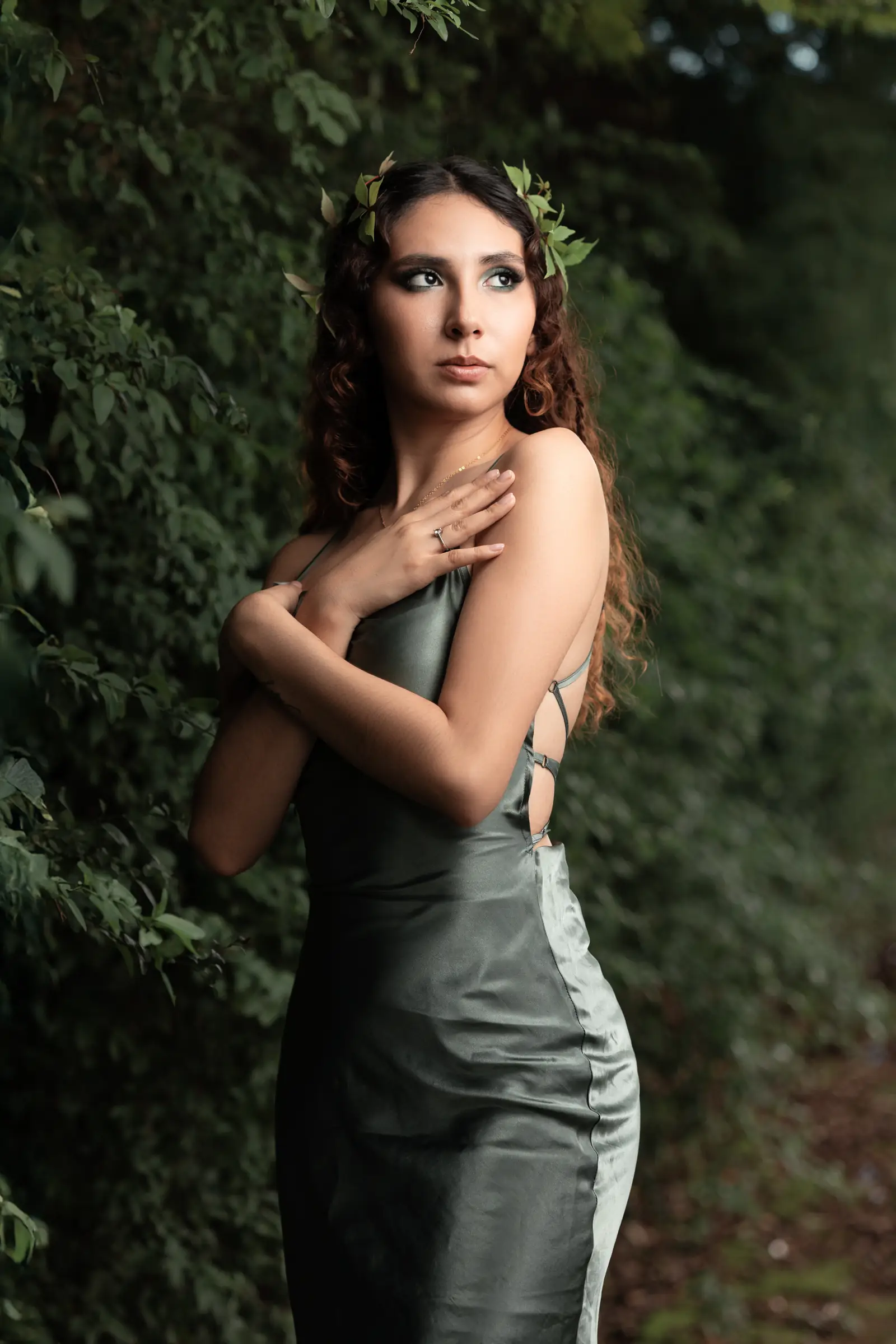 Mujer con corona de hojas y vestido verde entre follaje
